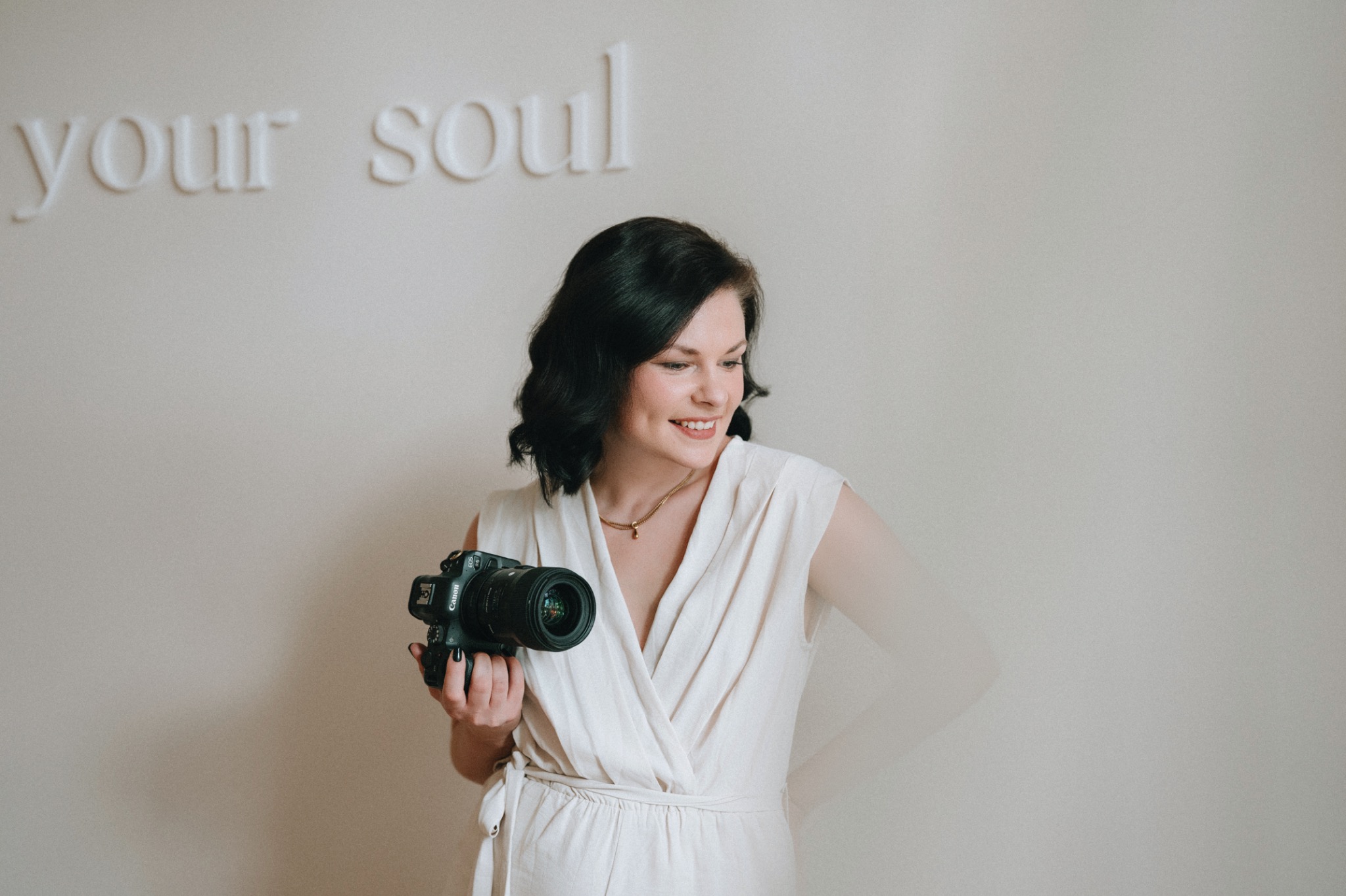 Laura Jankowski lächelnd mit ihrer Kamera vor dem Schriftzug soul – Portrait von Julia Funke